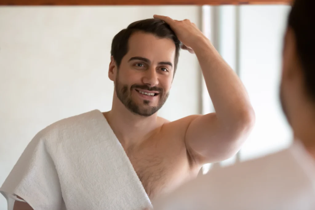 A man admires his fuller hair after a Keralase hair restoration treatment.