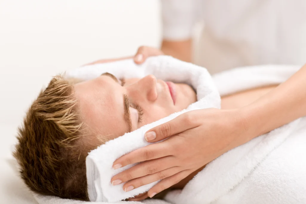 A man receiving a relaxing facial treatment with warm towels.