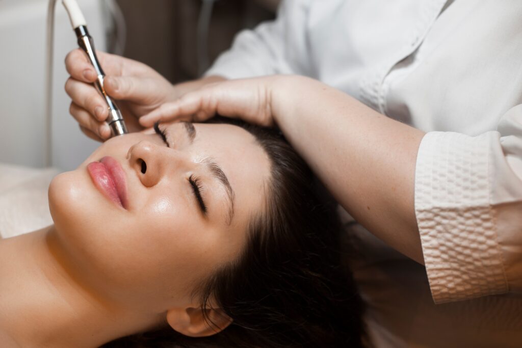 A professional performing microneedling treatment on a woman’s face during a relaxing skincare session in a clinic.